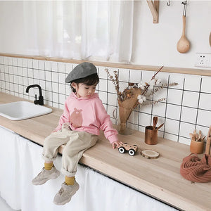 Child wearing beige corduroy trousers with rolled hems