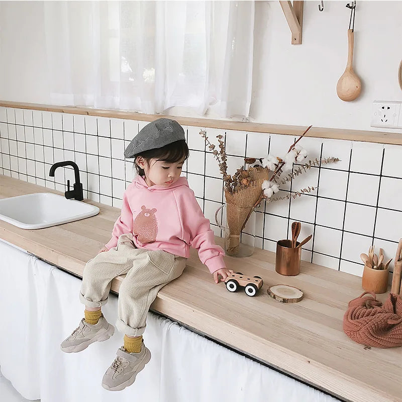Child wearing beige corduroy trousers with rolled hems