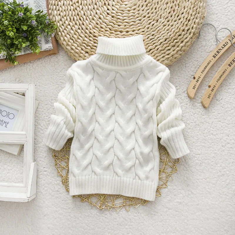 White cable-knit children’s sweater with a roll-neck collar