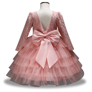 Back of a pink children's lace party dress showing a V-shaped back and large bow